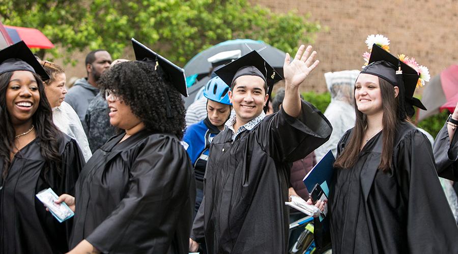 CCC graduate standing in a group waving hi with his hand